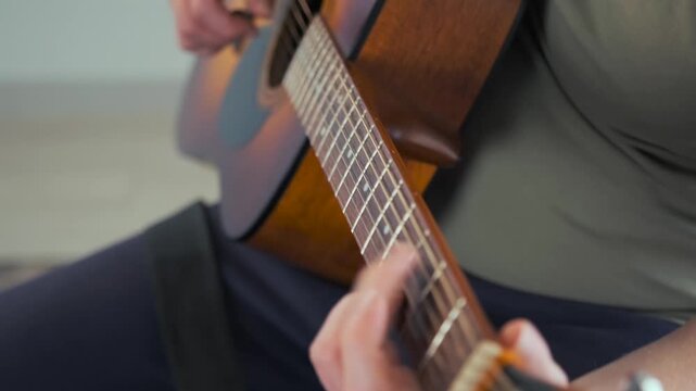 Close-up view of a man hands gently strumming an acoustic guitar. Soft focus and warm lighting create a nostalgic, soulful mood in the spirit of traditional bard music.