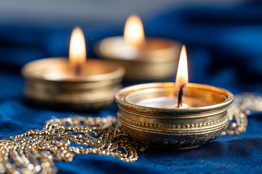 glowing candles in brass holders on rich blue velvet with gold sequin embroidery, traditional Diwali atmosphere, 