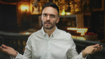 Fototapeta premium Young man in church making a knocking gesture, surrounded by religious icons and candles, evoking themes of faith and contemplation.