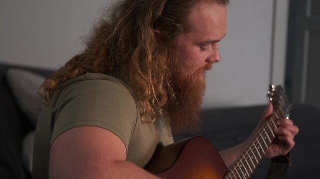 A red-haired bard with a long beard sings and plays a heartfelt acoustic song at home, close-up of his guitar playing and vocals, classic bard performance.