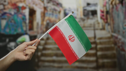 Man holding iranian flag on a city street, showcasing national pride amidst urban background.