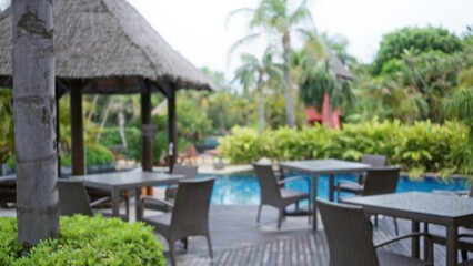 Blurred view of a tropical luxury resort featuring defocused outdoor seating and lush palm trees highlighting an inviting hotel poolside atmosphere.