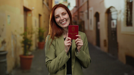 Redhead woman holding norway passport smiling on city street, showcasing travel readiness and excitement outdoors.