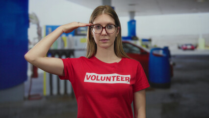 Blonde volunteer woman salutes with hand to forehead by petrol station building in broad daylight  dedication service. © Krakenimages.com