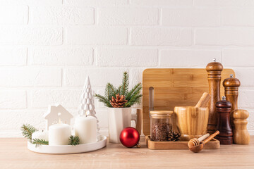 Stylish kitchen background decorated for the New Year and Christmas. wooden kitchen utensils set, lit candles on wooden countertop.