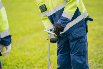 Electric utility worker using grounding equipment on grassy field during safety training or...