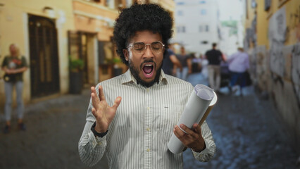 African american man holding blueprints, expressing on busy street in city setting.