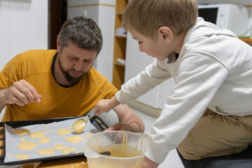 Father and son baking cookies together in kitchen