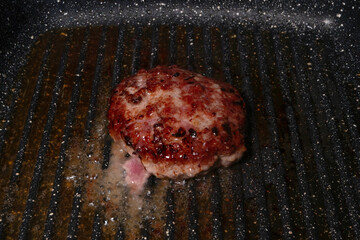 Juicy burger patty grilling in a hot pan