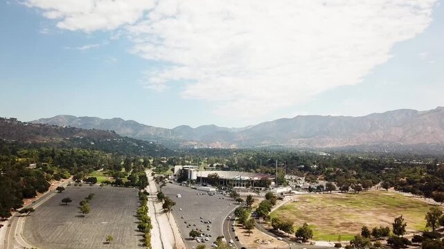 Rose Bowl football stadium in Pasadena at sunset time. Aerial approaching shot. Angeles national forest mountains in background. California, USA.