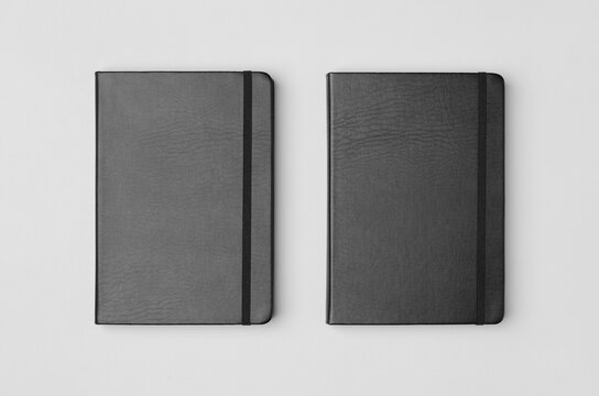 Mockup of two black notebooks from overhead on a gray background
