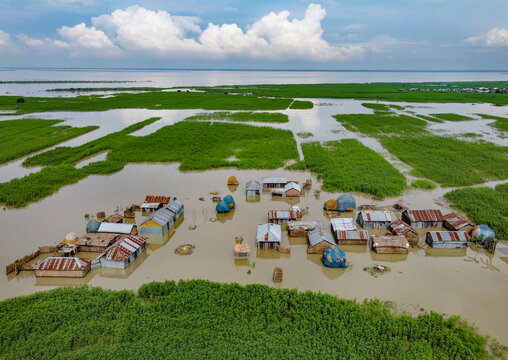 Sariakandi, Bangladesh - 15 July 2019: Aerial view of homes submerged in floodwaters, a stark tableau of resilience against the backdrop of a vast, watery expanse.