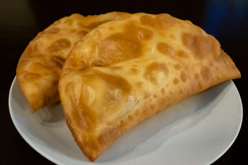 Two golden brown khachapuri pastries are displayed. This is a common bread in Georgia, often filled with cheese and other ingredients. This version is a deep fried delicacy.