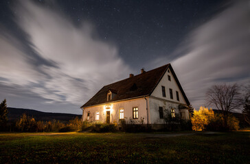 Vintage country house at night with clouds and stars. Cold autumn night