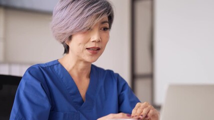 Adult Asian female healthcare professional provides remote medical advice during a virtual consultation from her modern office setting. - Powered by Adobe