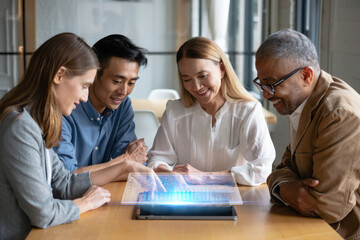 Diverse team collaborates on futuristic holographic display, sparking innovation and shared success in a modern office setting, driving forward future projects.