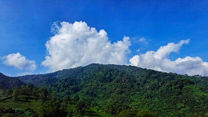 Mountains landscape. Panorama of beautiful countryside of Indonesia in sunny afternoon. landscape in mountains. grassy field and rolling hills. rural scenery with blue sky.