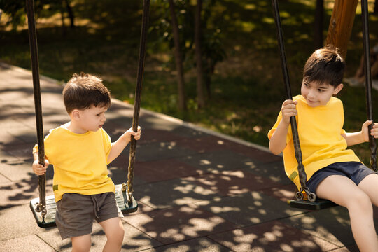 Happy children playing outdoors on playground swings and animal shaped seesaws. Siblings enjoy a sunny summer day full of fun and joy in the park. Concept of childhood, leisure and outdoor activity.
 - Powered by Adobe