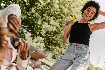 Fototapeta premium Friends enjoying a sunny summer picnic in the park while sharing laughter and good times