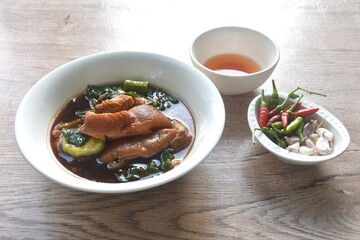 braised slice pork leg stew black Chinese herb soup and kale dipping  mixed spicy sour chili sauce on plate eat couple fresh garlic
