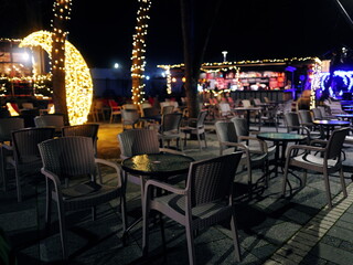 Charming Outdoor Café Setting with Festive String Lights and Empty Tables Under the Night Sky