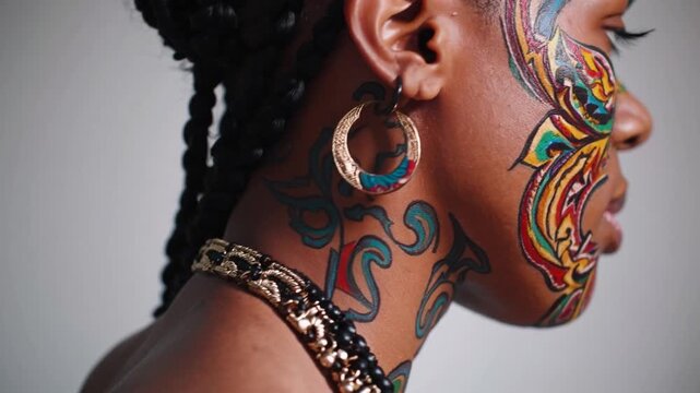 Cultural heritage and self expression intertwine as a young Black woman displays intricate and colorful temporary tattoos adorning her face and neck, complemented by traditional jewelry