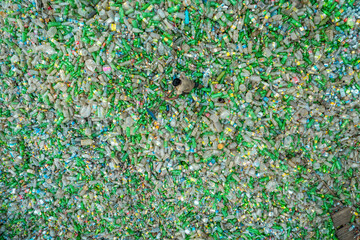 Bogura, Bangladesh - 10 August 2022: Aerial view of a sea of crushed glass bottles, their fragments glinting in shades of green and white under the open sky.