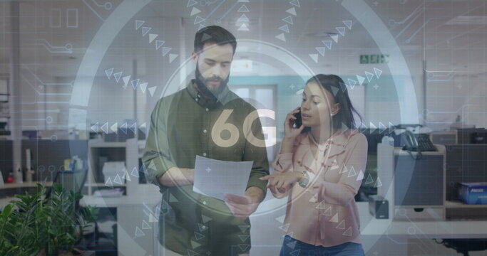 Colleagues discussing document while speaking into smartphone in office workspace, with 6G graphics - Powered by Adobe