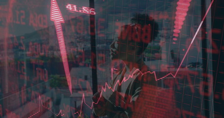 Standing businesswoman analyzing red stock graphs, numeric tickers, upward arrow at office window