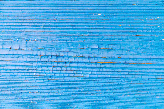 Cracks in blue paint on old wooden surface, background texture.