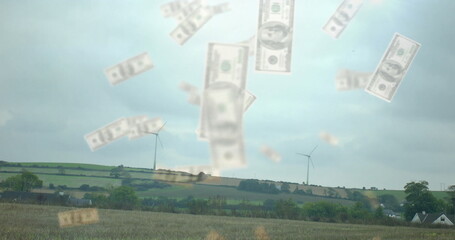Floating cluster of US dollar bills hovering above farmland, with turbines, hedgerows and rooftops