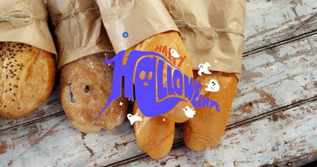 Fototapeta premium Displaying paper-wrapped loaves on chipped blue wooden table showing Halloween ghost graphic