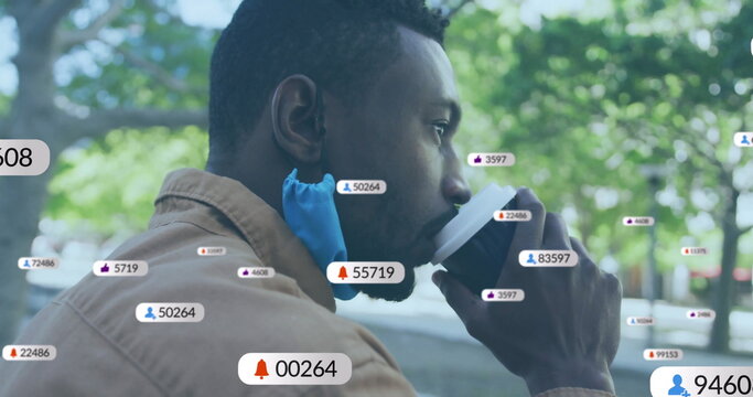 Sipping coffee from cup, man with blue face mask at park bench with floating social icons