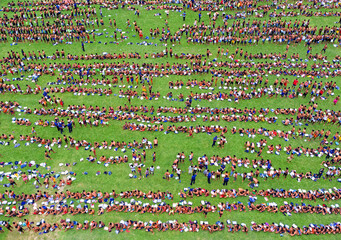 Bogura, Bangladesh - 07 March 2019: Aerial view of a multitude of people gathered on a vibrant green field, their forms creating intricate patterns from above, dotted with blue uniformed individuals.