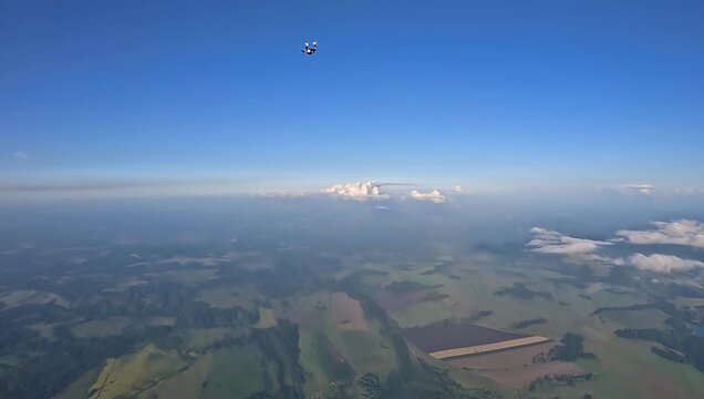 A group of parachutists jumps from a helicopter into the endless clear blue sky, capturing the thrill and teamwork of an extreme aerial adventure.