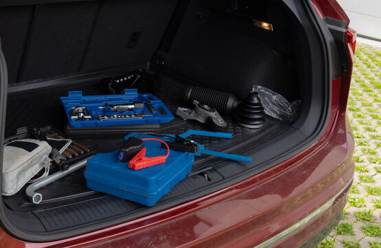 Trunk of car with automotive tools including wrench set and jumper cables