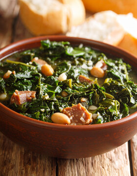 A close-up of Matapa, a rich, dark green cassava leaf stew with ground peanuts, served in a rustic bowl.