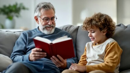 Elderly man reading book to young boy while sitting on a sofa at home - Powered by Adobe