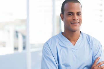 Obraz premium African American man in blue scrubs standing on hospital balcony overlooking skyline, copy space