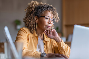 Middle-aged African-American woman creating email templates for customer service follow-ups, testing tone and format
