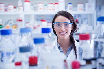 Reagent bottles and glass flasks are resting on cluttered laboratory bench, with colored screw caps
