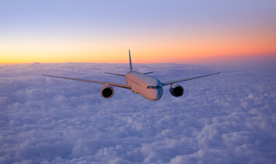 Airplane flying over tropical sea at sunset