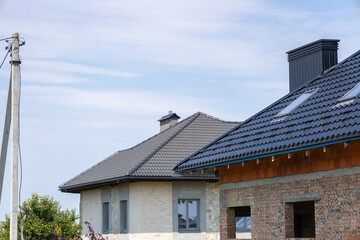 New residential buildings showcase modern roofing designs under a bright blue sky in a peaceful suburban neighborhood