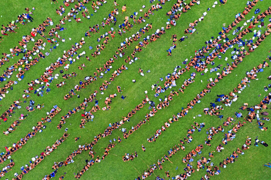 Bogura, Bangladesh - 07 March 2019: Aerial view of densely packed rows of people creating a striking pattern against the vibrant green grass, a sea of humanity.