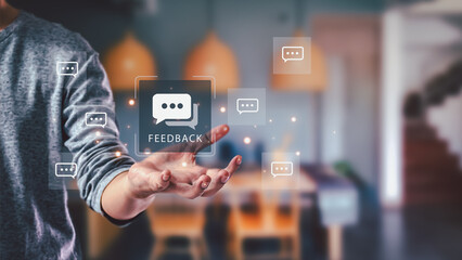 Customer feedback concept. A man indoors presents a virtual interface with speech bubble icons, offering a way to give online reviews and evaluate service satisfaction.