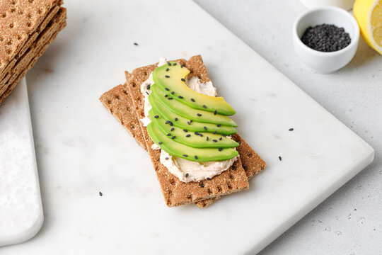 Toast with fresh avocado and cheese on bread on white board. Light photography