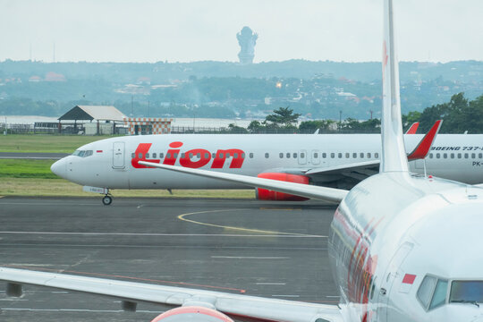 Bali, Indonesia &ndash; December 31, 2024: The Lion Air logo and brand displayed on an aircraft at I Gusti Ngurah Rai International Airport, with a blurred view of the Garuda Wisnu Kencana statue in the bac