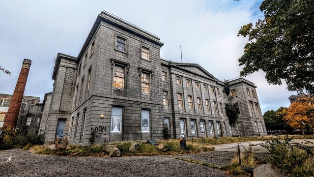 Eerie abandoned medical centre listed building in Scotland. Apocalyptic, boarded up, vandalised graffiti. Imposing architecture, derelict historic Aberdeen Woolmanhill Hospital in dilapidated state.