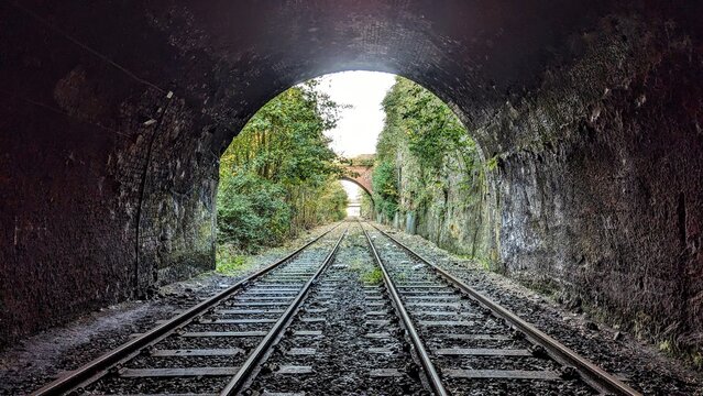 Derelict deserted railway, light at the end of the tunnel. Crown Street arch entrance, Liverpool. Abandoned parallel straight train tracks inside dark bridge archway. Rail journey, horizon perspective