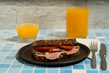 Healthy and delicious breakfast with whole wheat ham and tomato sandwich and orange juice